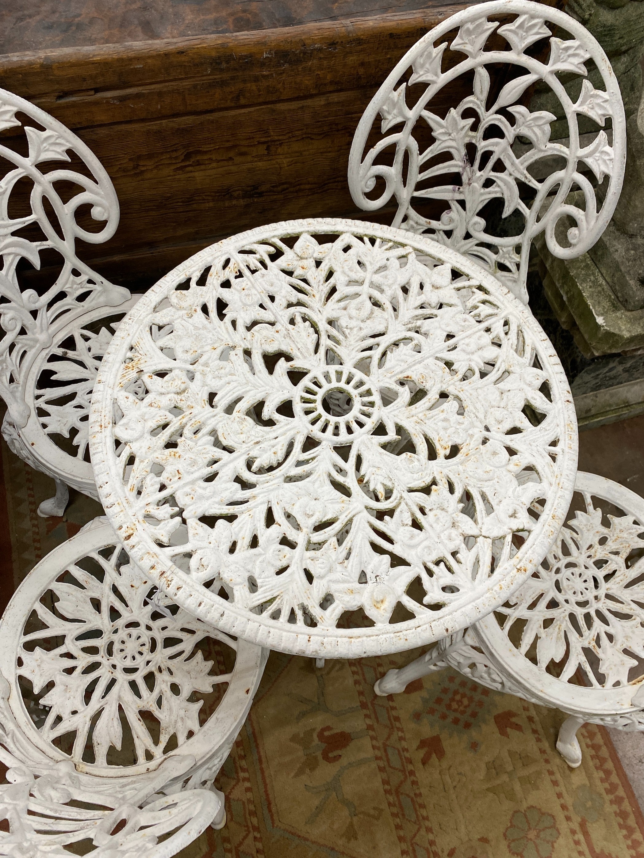 A Victorian style painted cast iron circular garden table, diameter 62cm, height 67cm together with four matching chairs